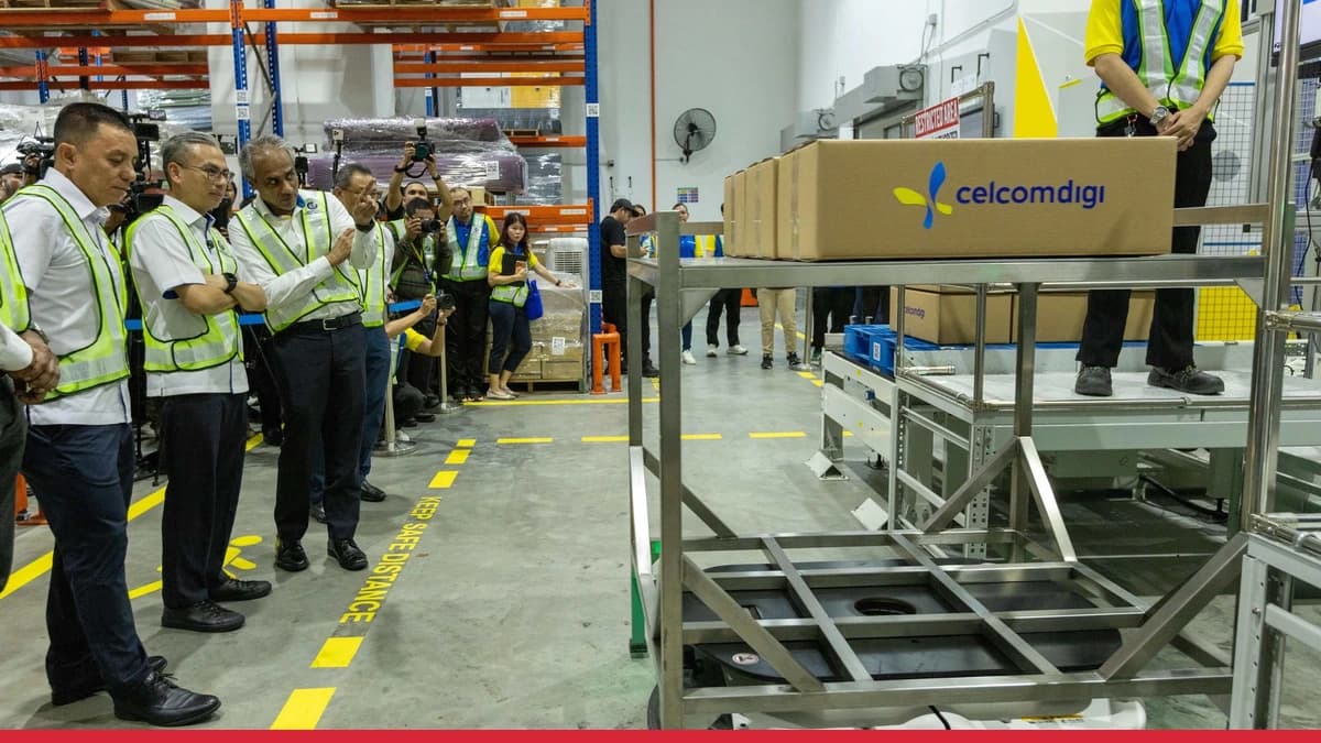 Workers and automated systems inside CelcomDigi's industrial 5G smart warehouse deployment