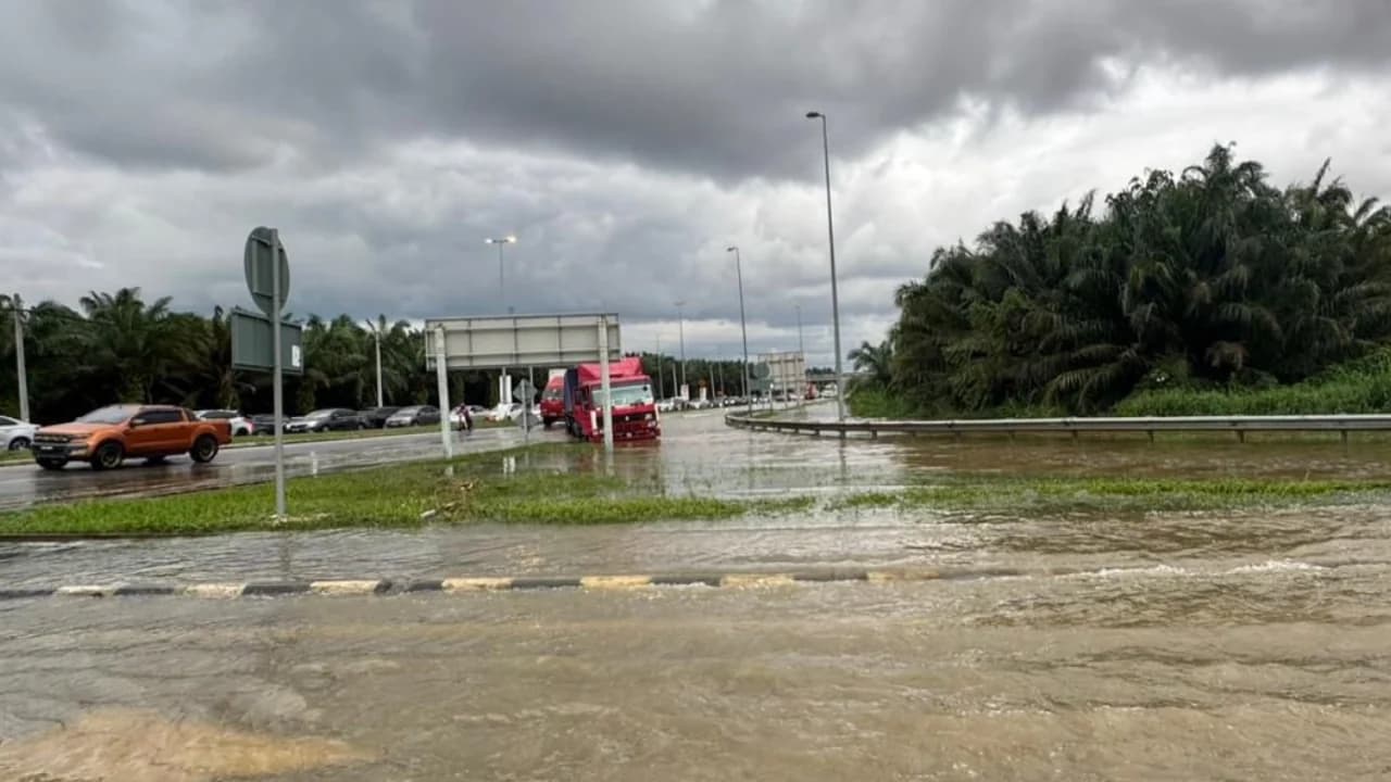 Flood water covers a road near a Selangor interchange beneath dark storm clouds