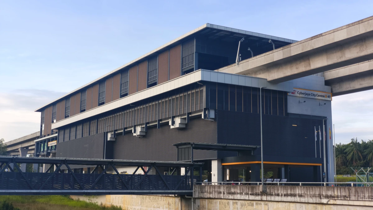Cyberjaya City Centre MRT station, a long dark station building with an elevated concrete viaduct curving above it, under a clear blue sky