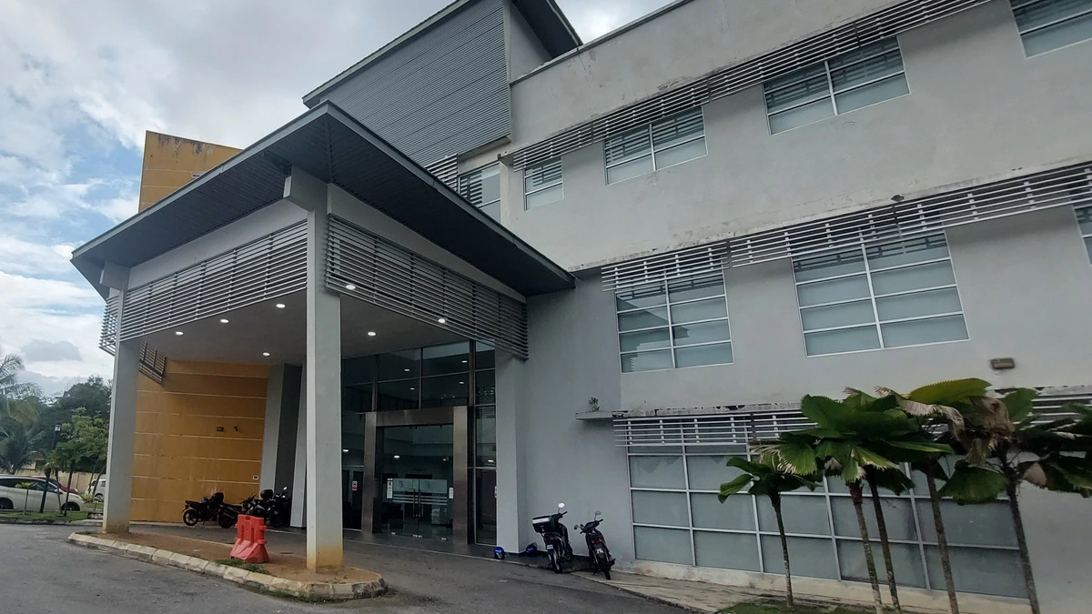 The grey three-storey laboratory building of UKM's Faculty of Science and Technology, with a covered entrance, motorcycles parked outside and palms along the wall