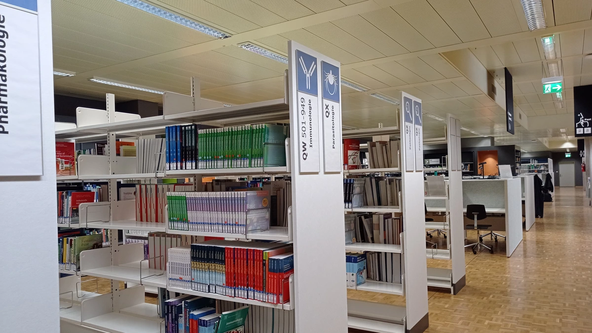 Library shelves with subject signs for pharmacology, immunology and parasitology in a university medical library