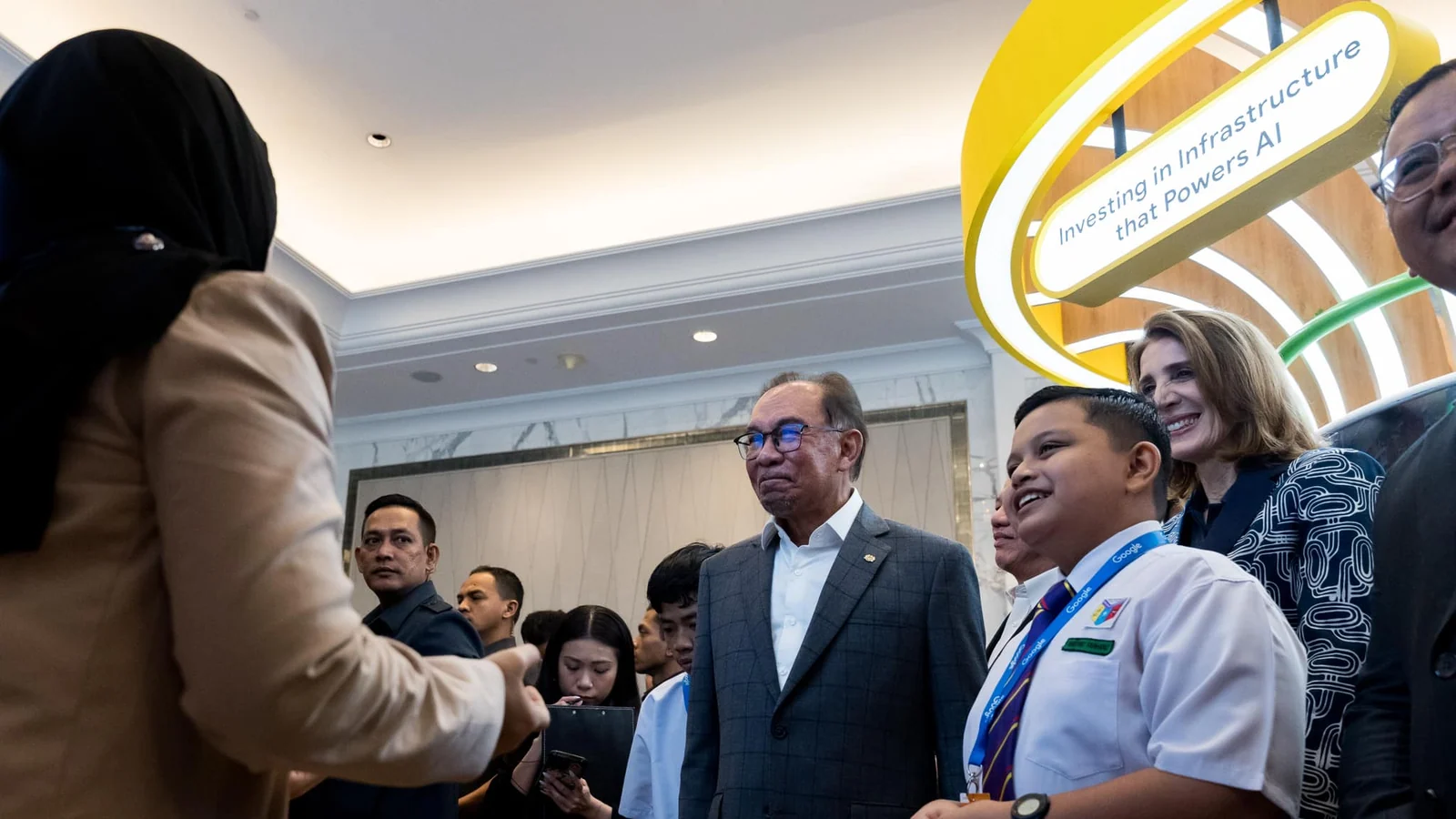 Anwar Ibrahim and Ruth Porat speak with a Malaysian student at Google's later AI education event
