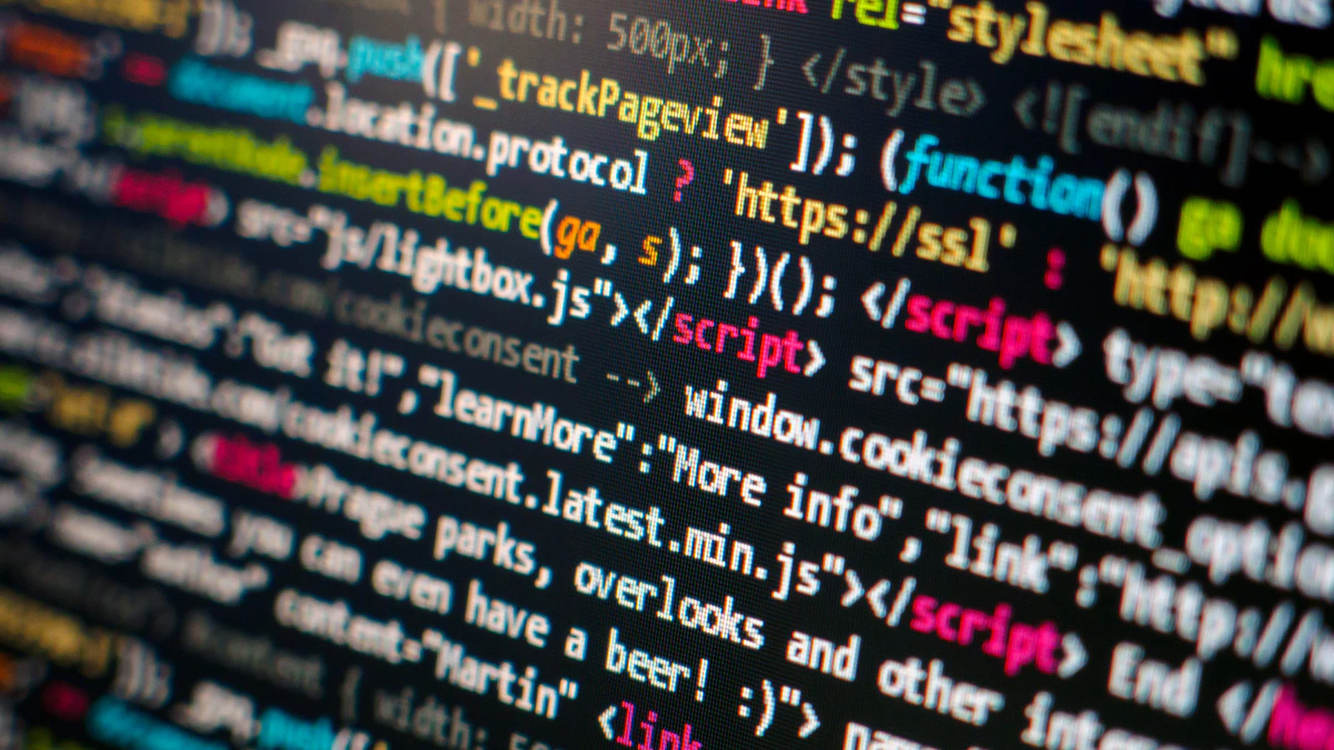 A close-up of a computer display filled with syntax-highlighted HTML and JavaScript, the coloured tags and function calls running diagonally out of focus towards the right of the frame