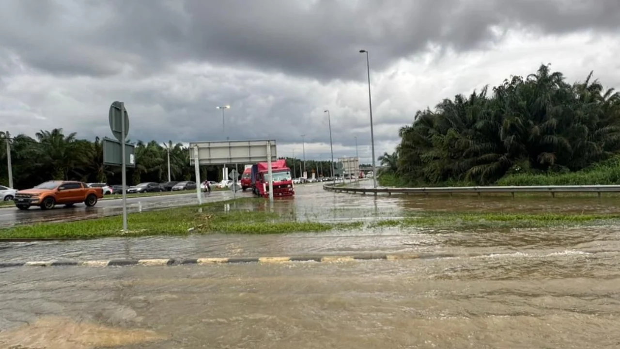 Flood water covers a road near a Selangor interchange beneath dark storm clouds