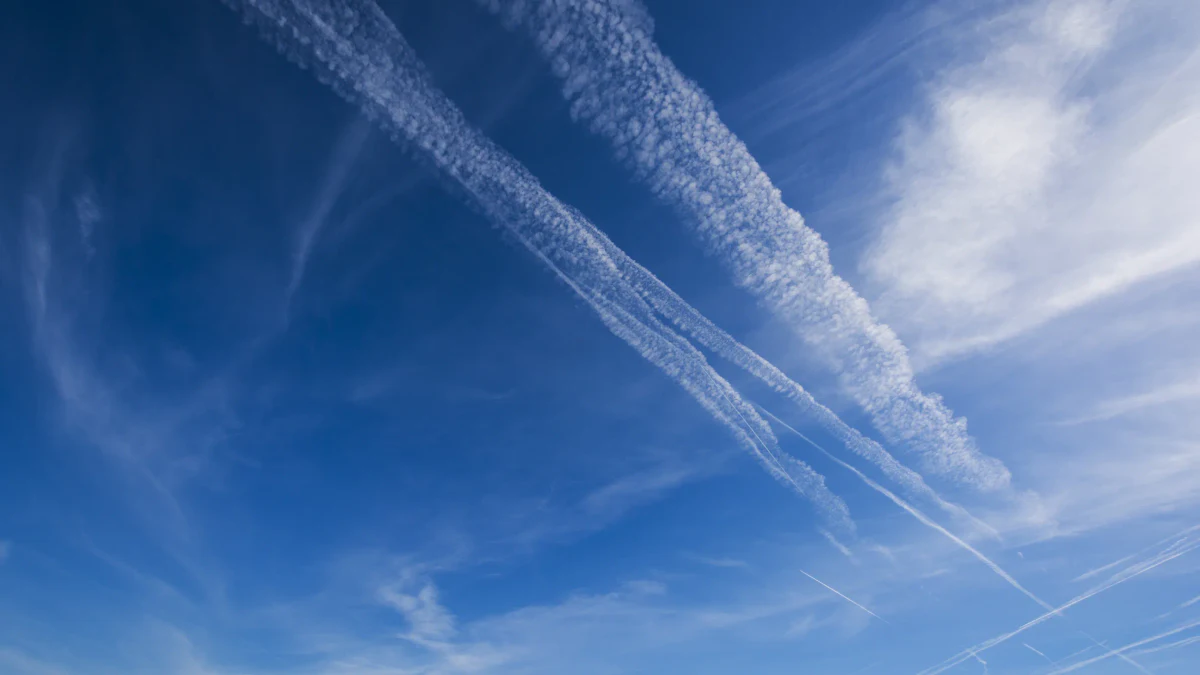 Persistent aircraft contrails spreading into cloud across a blue sky