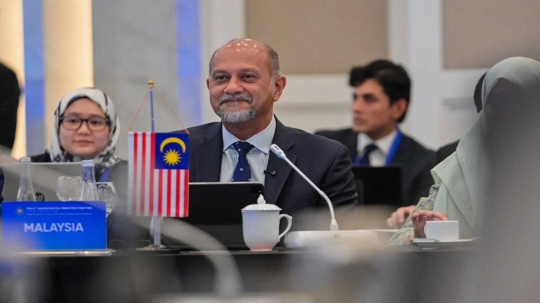 Digital Minister Gobind Singh Deo sits behind the Malaysian flag at the sixth ADGMIN in Hanoi