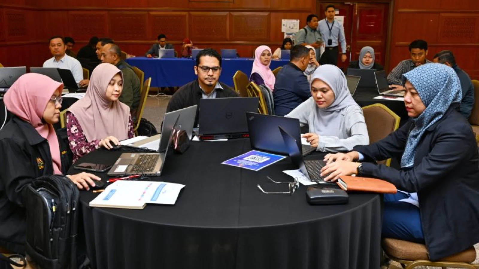 Five Malaysian public officers use laptops together during practical generative AI training in Putrajaya