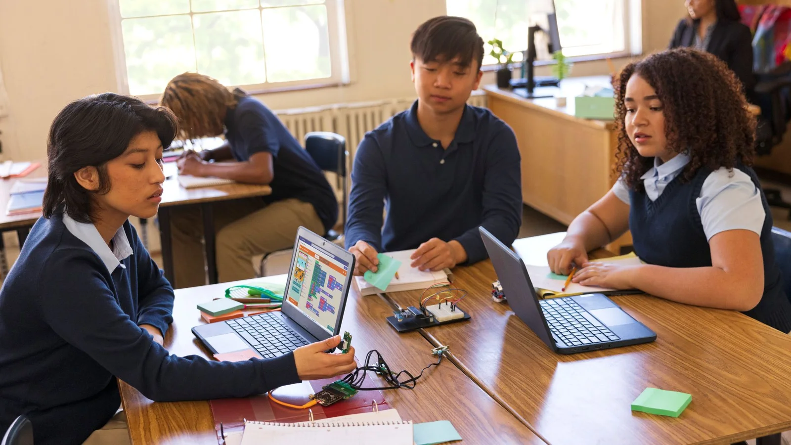 Students collaborate with laptops and electronics in a classroom in an official Microsoft Education photograph