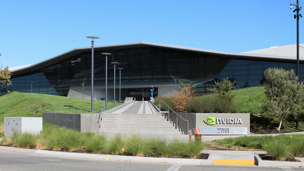 A long, low building with an angular dark glass facade behind grassy mounds, reached by wide concrete steps beside a sign reading NVIDIA 2788