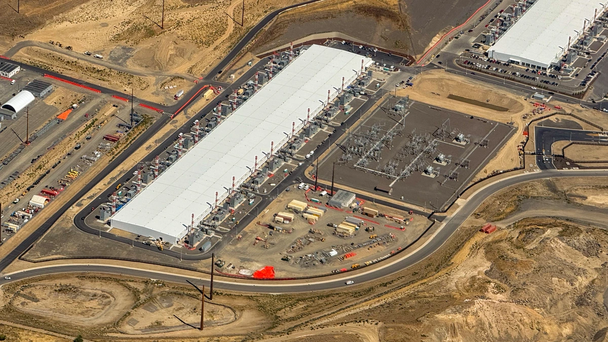 Aerial view of a long white-roofed Microsoft Azure datacentre building lined with rooftop equipment, beside an electrical substation and a second datacentre, on dry brown hills in Wenatchee, Washington
