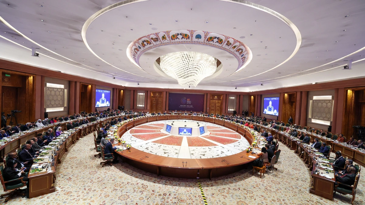 Wide view of a circular conference table in a large hall with a chandelier and decorated ceiling, with delegates seated around the outer ring