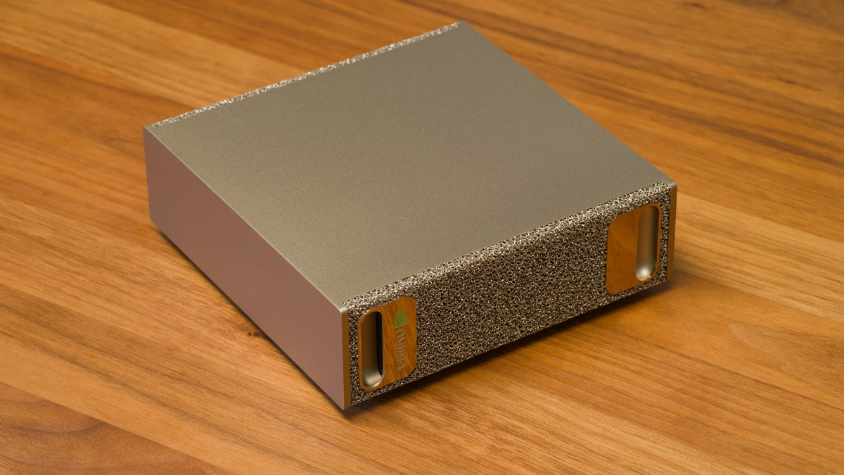 A small gold-coloured NVIDIA DGX Spark desktop computer with a metal foam front panel, photographed at an angle on a wooden table