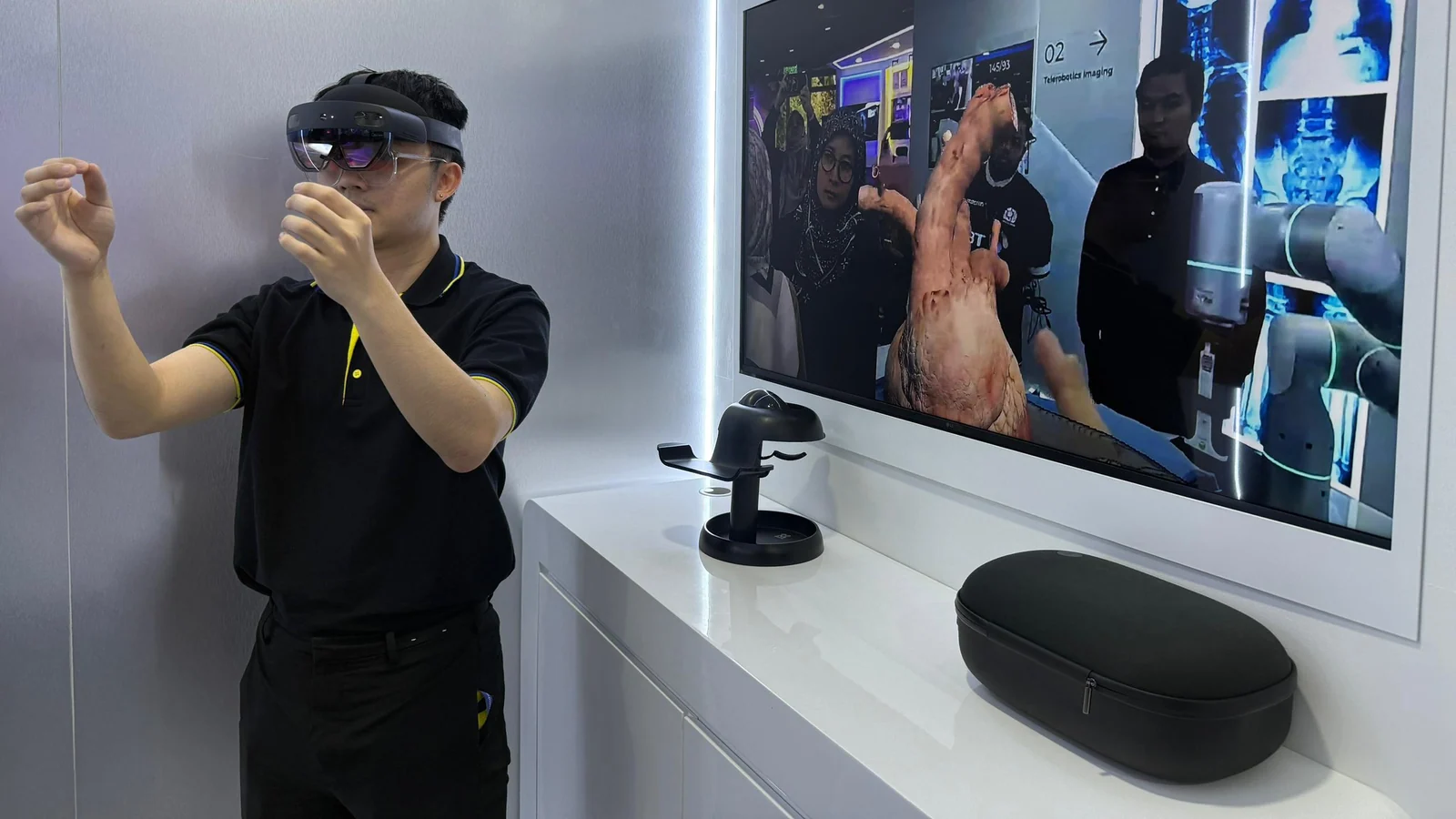 A Universiti Malaya visitor uses a mixed-reality headset beside a three-dimensional heart display