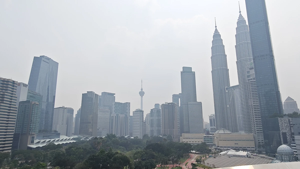 Hazy view of the Petronas Twin Towers, KL Tower and office blocks above KLCC Park in Kuala Lumpur