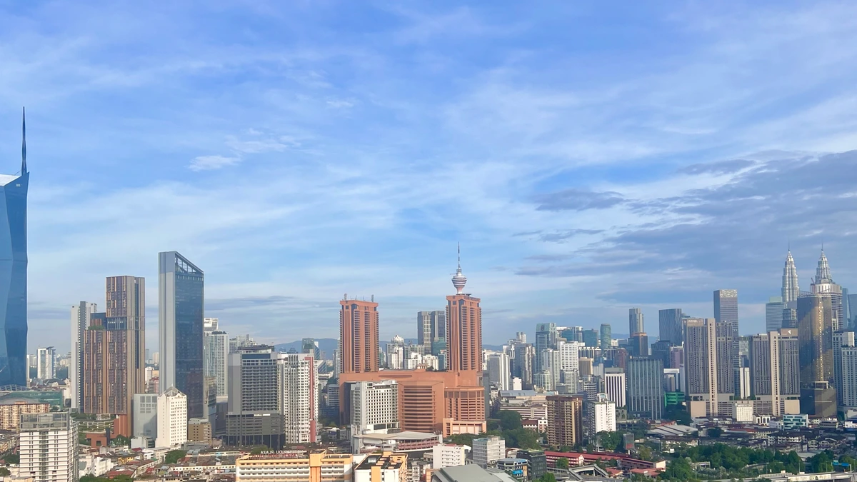 The Kuala Lumpur skyline in morning light, with Merdeka 118 and the Petronas Towers rising above a dense spread of low-rise shophouses and mid-rise commercial blocks
