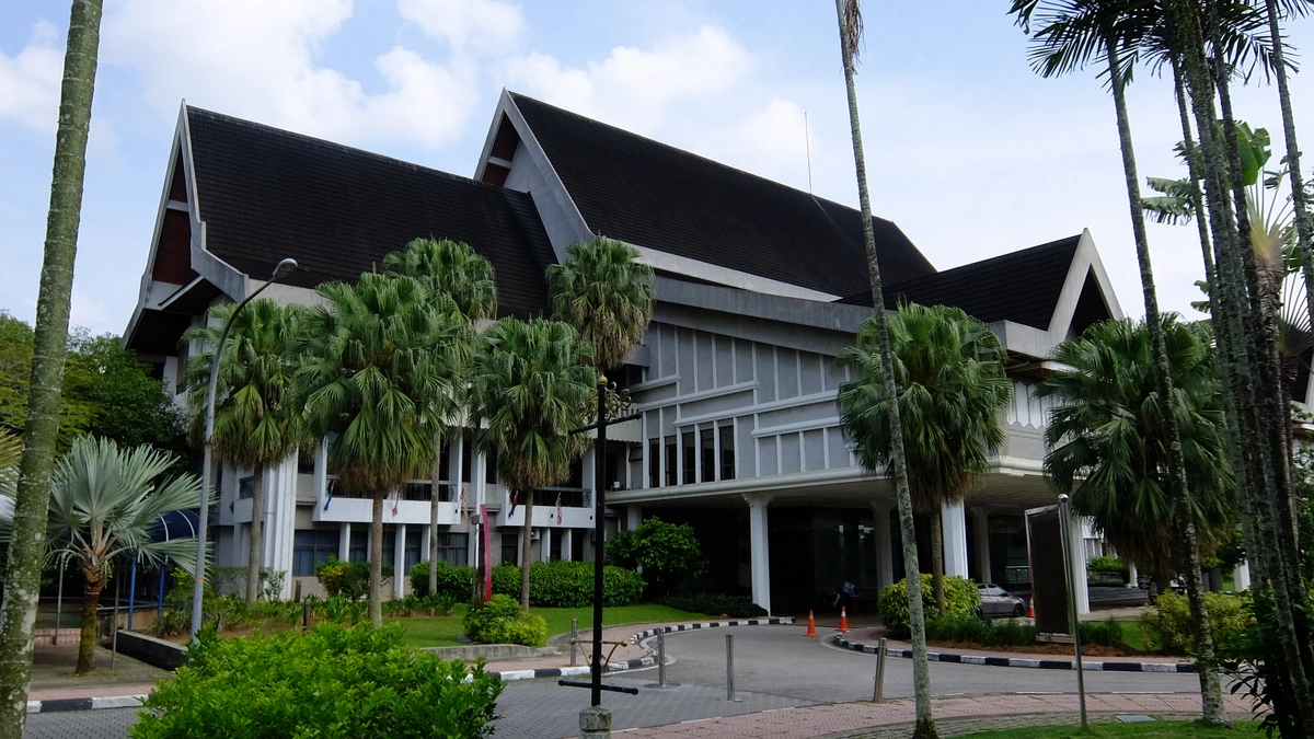 Sultan Ibrahim Chancellor Building at Universiti Teknologi Malaysia, a hall with a dark pitched roof and white columns among palm trees