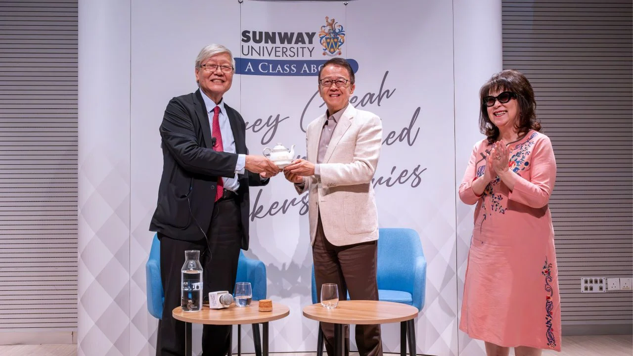 A token of appreciation is presented on stage in front of the Jeffrey Cheah Distinguished Speaker Series backdrop