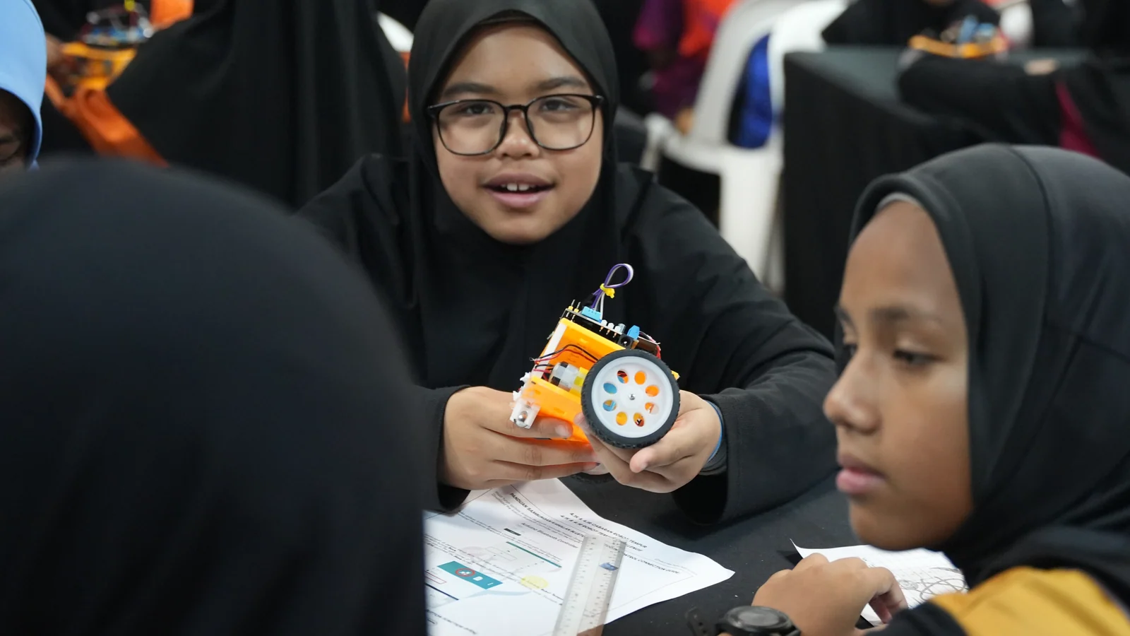 A student team examines a wheeled robot during the Southern Zone Techlympics competition