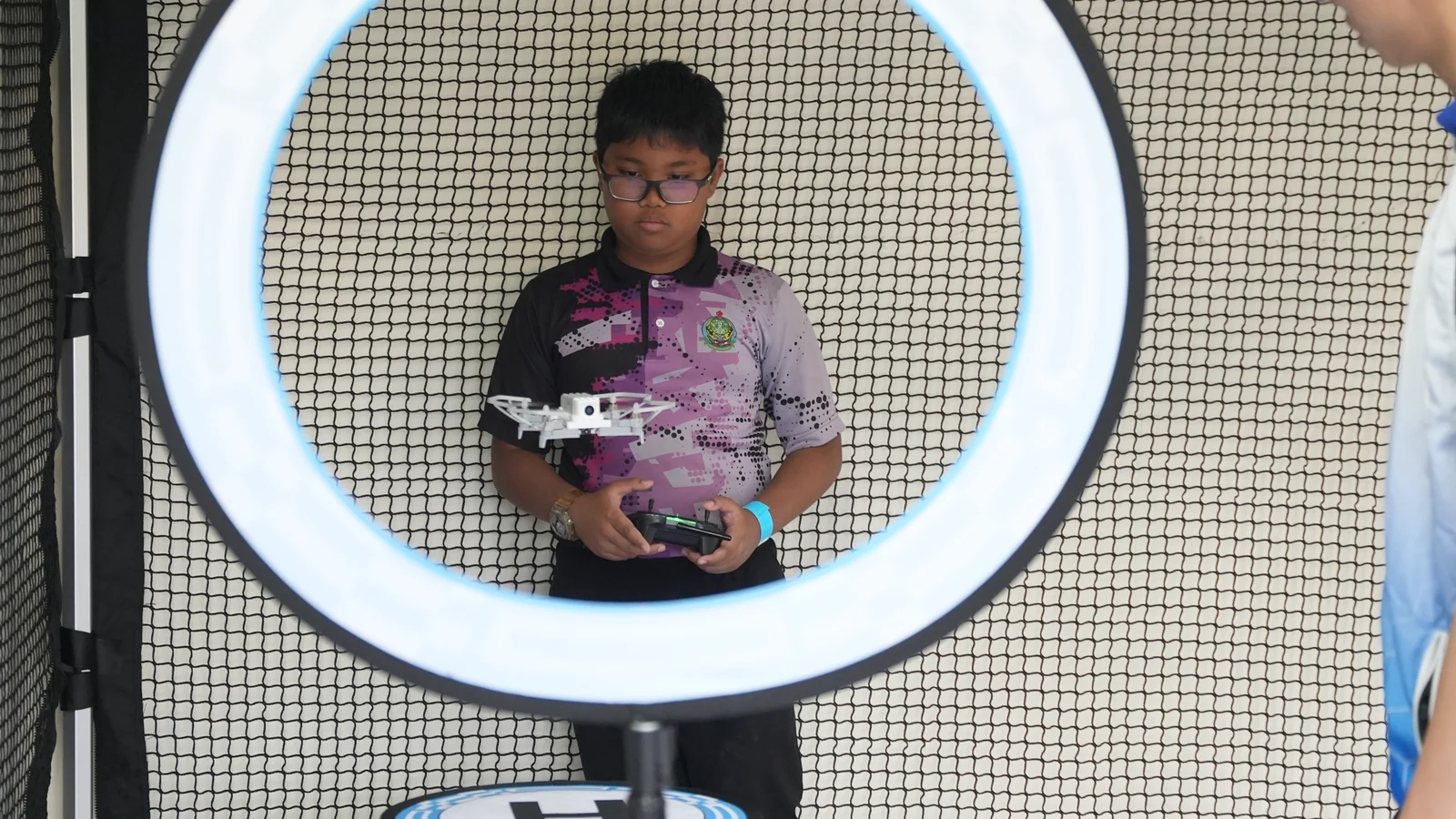 A Southern Zone Techlympics participant pilots a small drone through an illuminated circular gate