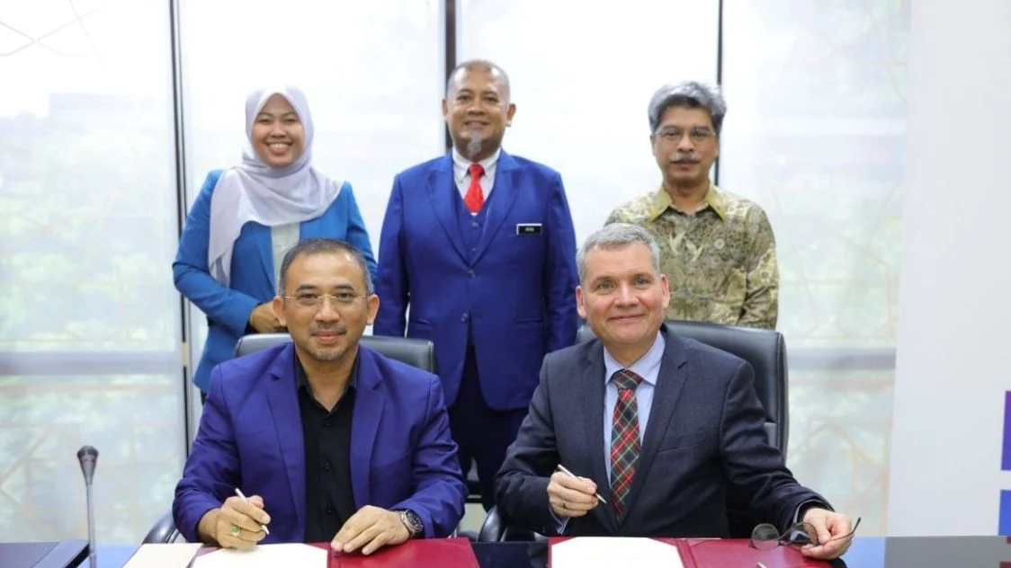UKM and QuantumX representatives sit with the letter of intent while university witnesses stand behind them