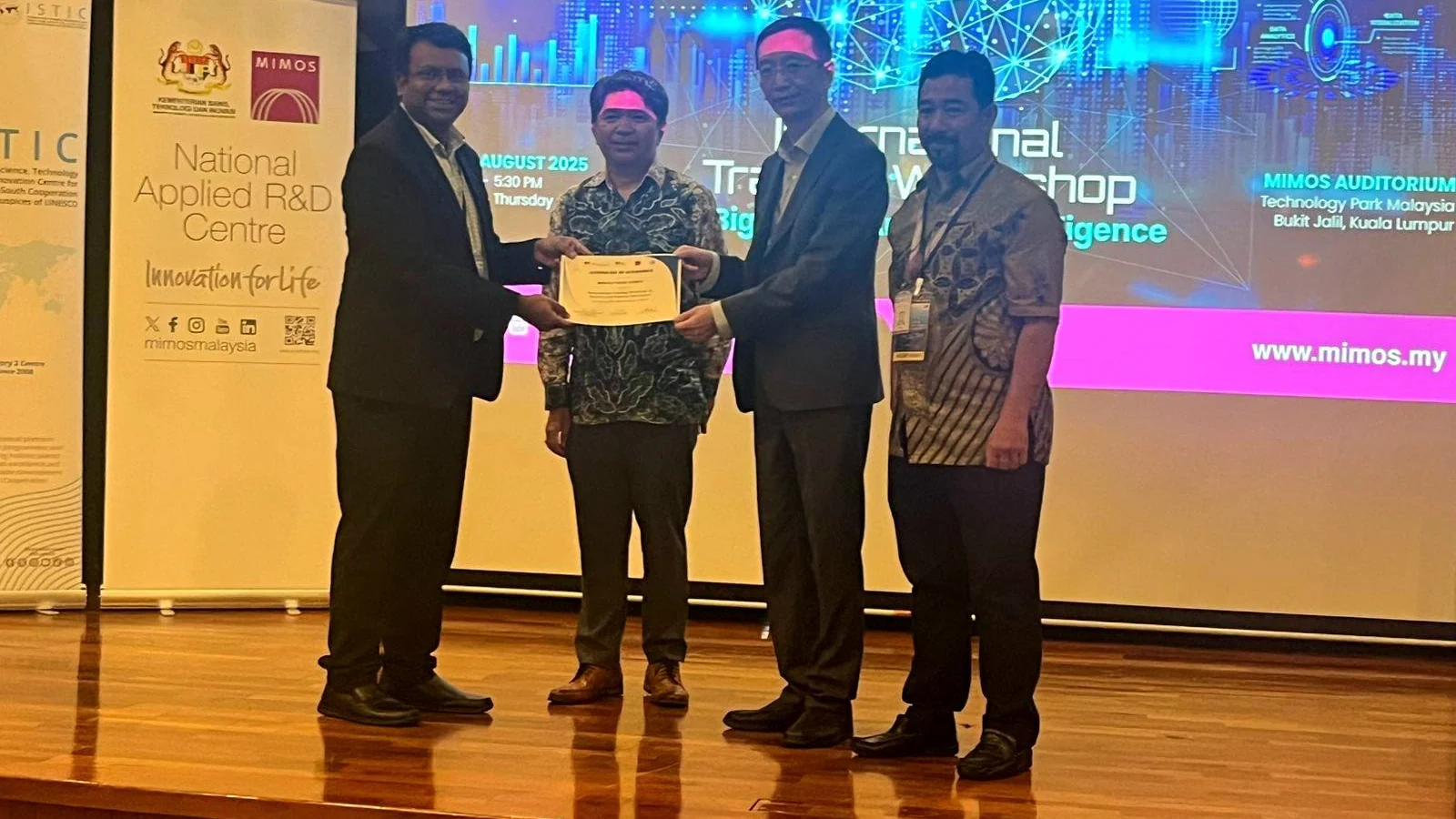 Representatives present a workshop certificate on stage at the MIMOS auditorium in Kuala Lumpur
