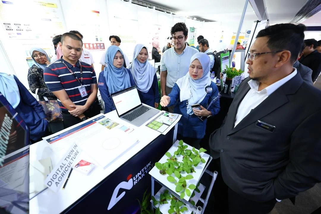UPM staff and visitors discuss a technology exhibit at the AI programme