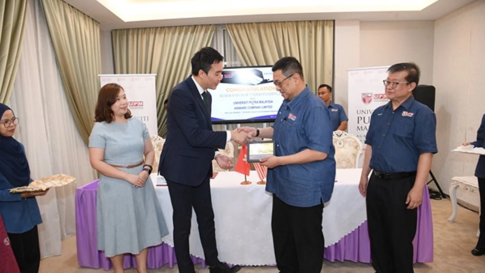 Aniware and UPM representatives exchange a commemorative item after the veterinary AI collaboration ceremony